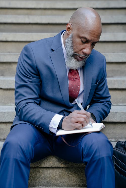 Free Man in Blue Suit Writing on a Notebook Stock Photo
