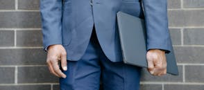 A Man in Blue Suit and Blue Pants Holding a Laptop