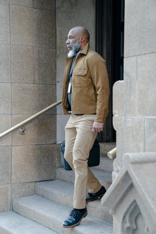 Man Wearing a Brown Jacket Walking Down the Stairs