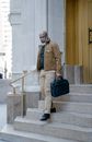 Bearded Man in Brown Jacket Walking Down the Stairs