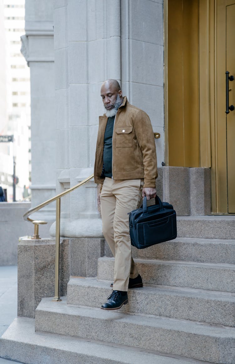 Bearded Man In Brown Jacket Walking Down The Stairs