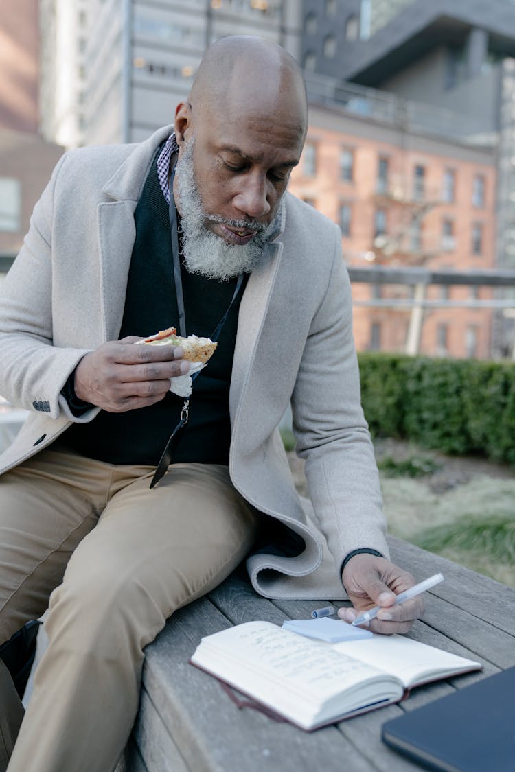 Man Eating A Sandwich While Writing