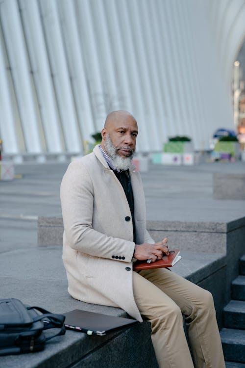 A Man in Beige Suit Sitting on Gray Concrete Bench