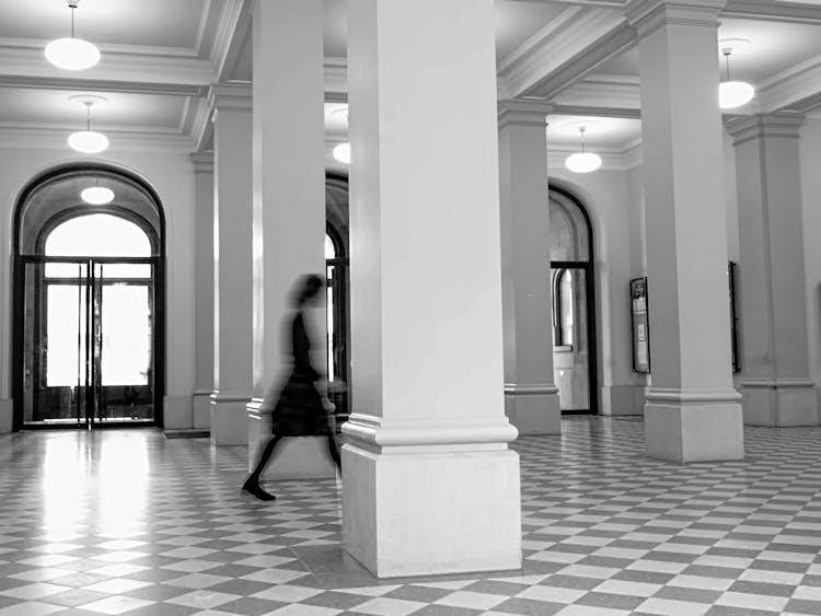 Black And White Photo Of A Corridor With Checked Tiles On Floor