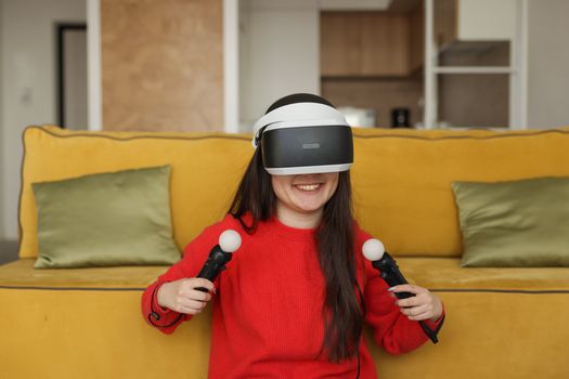 Smiling woman exploring virtual worlds with VR headset and controllers in a living room.