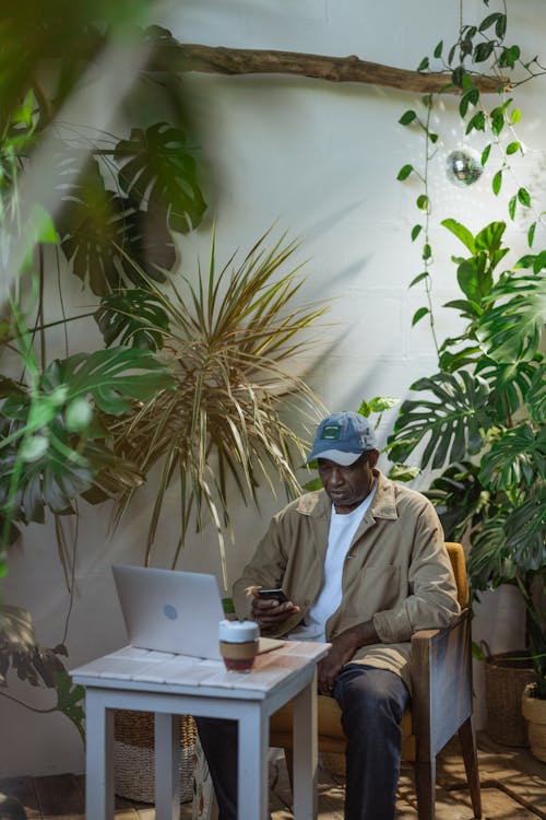 A Man Sitting on a Wooden Chair at a Wooden Table With a Laptop
