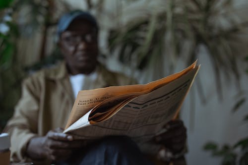 Free Low Angle Photo of Man Reading Newspaper Stock Photo