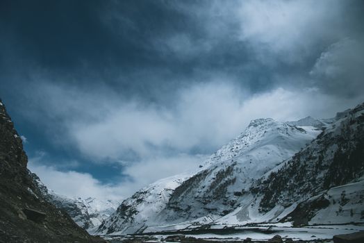 Stunning view of snowy mountains with blue sky and white clouds.