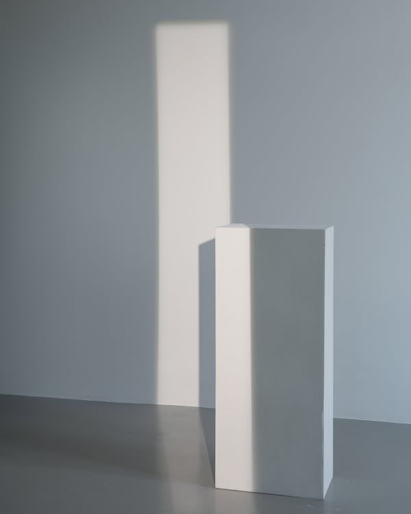 White Pillar Stand on Brown Wooden Table
