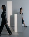Women in Black Clothes Walking Near a Plinth
