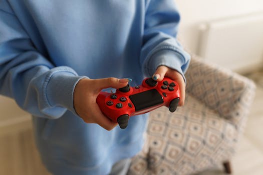 A person holding a red gaming controller indoors, showcasing a cozy gaming setup.
