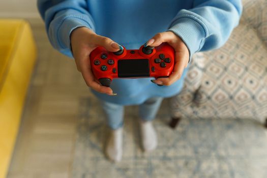 Person holding a bright red gaming controller indoors, focusing on gameplay.