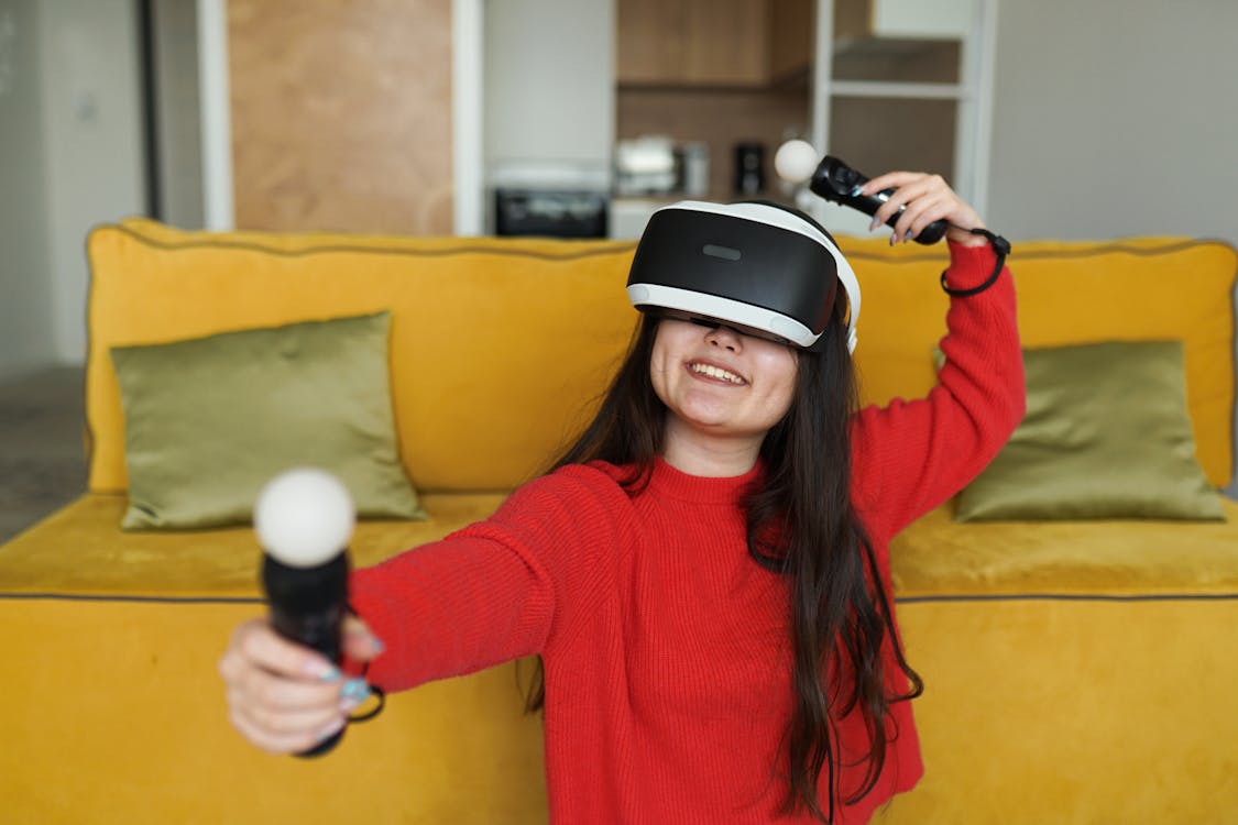 Woman in Red Sweater Wearing White and Black VR Goggles