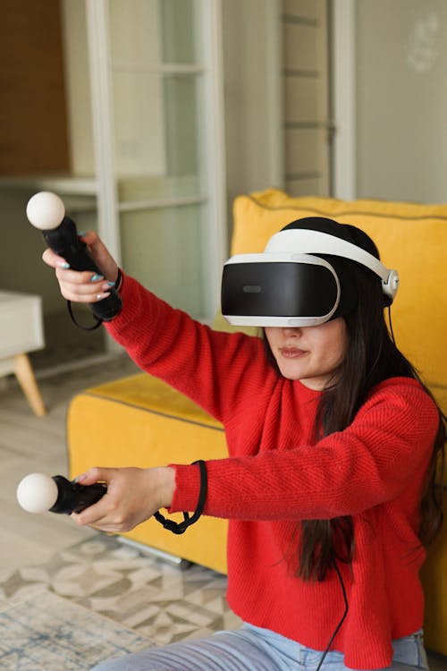 Woman in Red Long Sleeves Using Virtual Reality Goggles and Controllers
