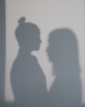 Two women's shadows cast on a wall creating an artistic silhouette effect.