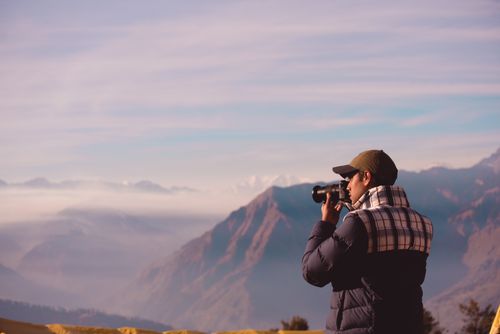 Free A man with a camera captures a stunning mountain view on a clear day. Stock Photo