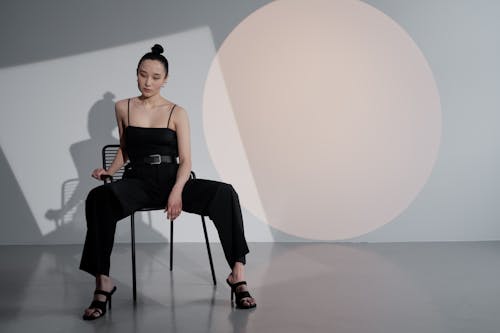 Woman in Black Jumpsuit Sitting on a Black Chair