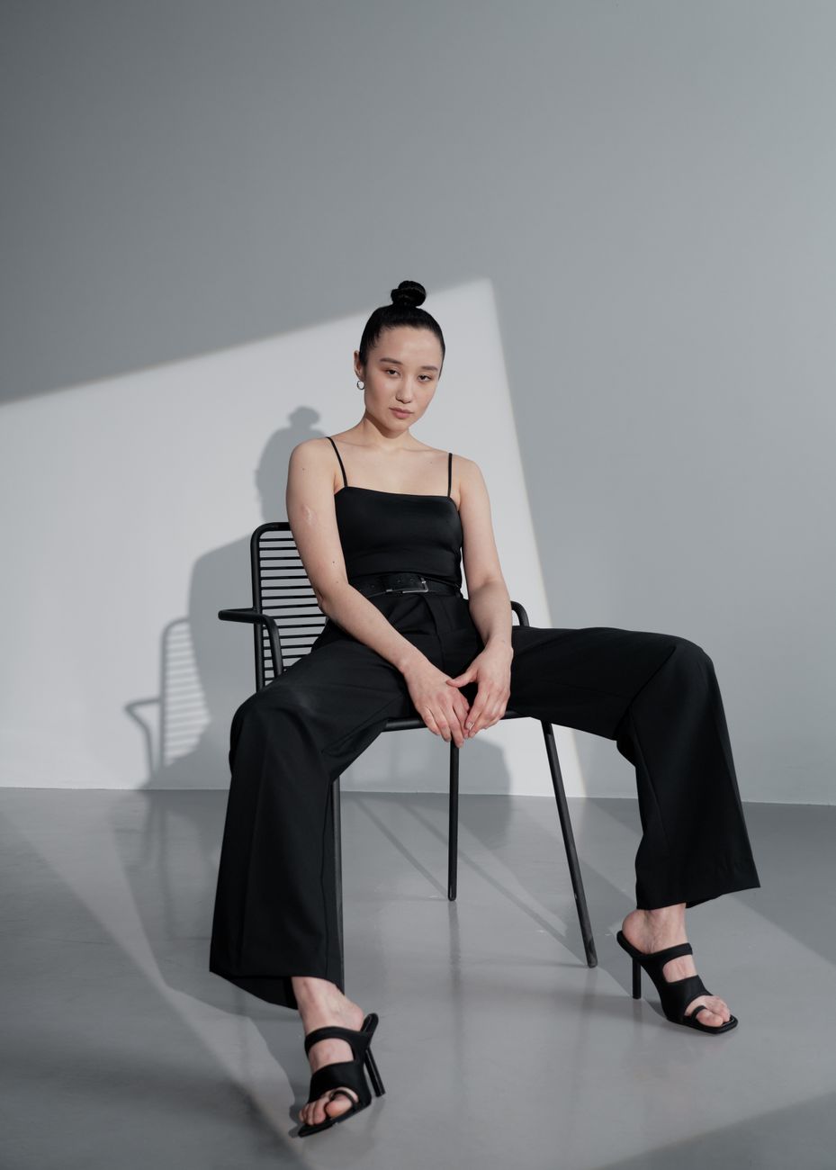 Stylish Asian model in a studio setting, showcasing fashion with dramatic lighting.
