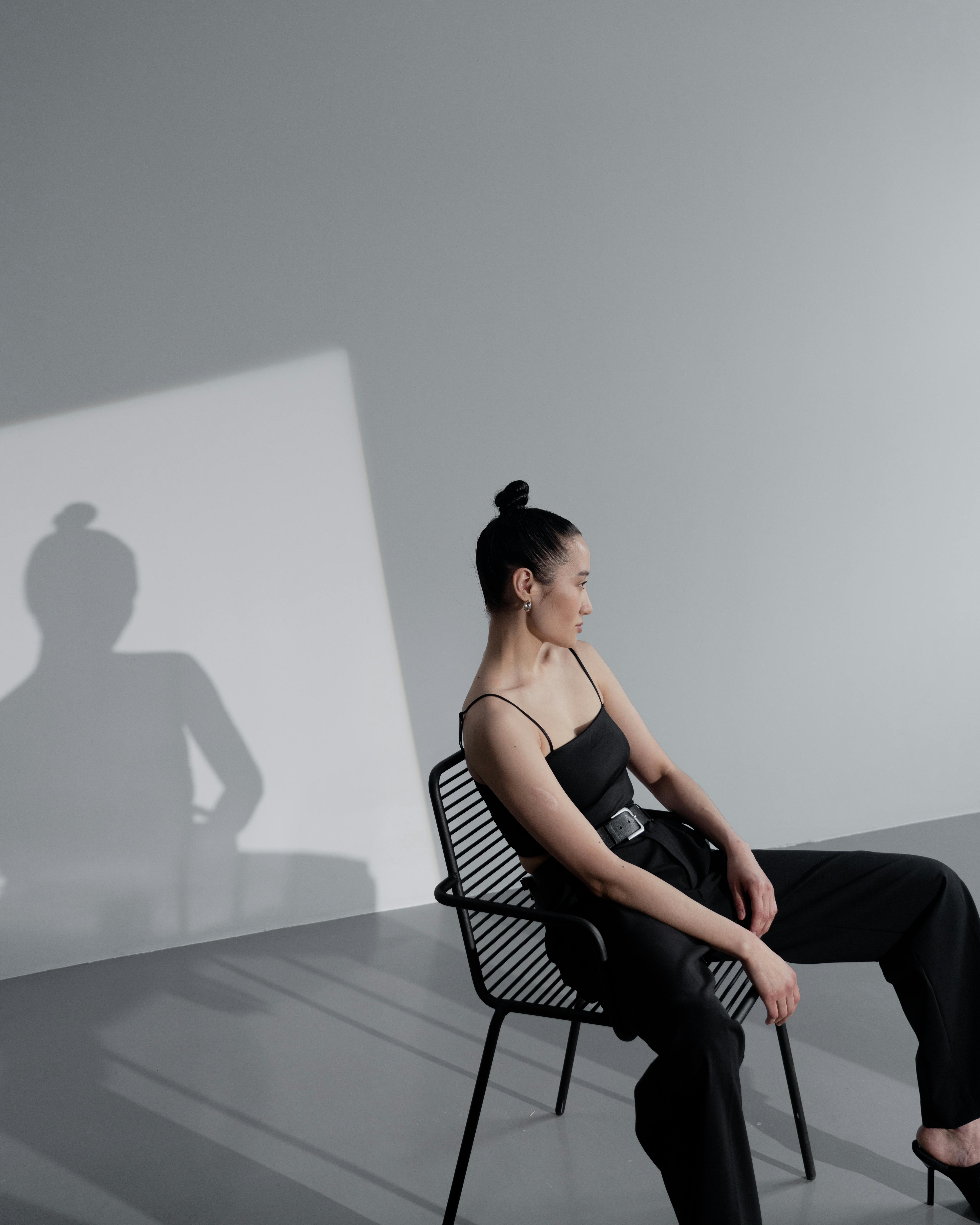 a female model in black outfit sitting on a chair