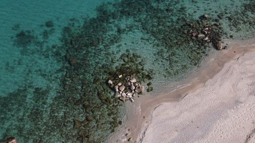 Free Aerial shot of a rocky beach in Soverato, Calabria, Italy with clear turquoise waters. Stock Photo