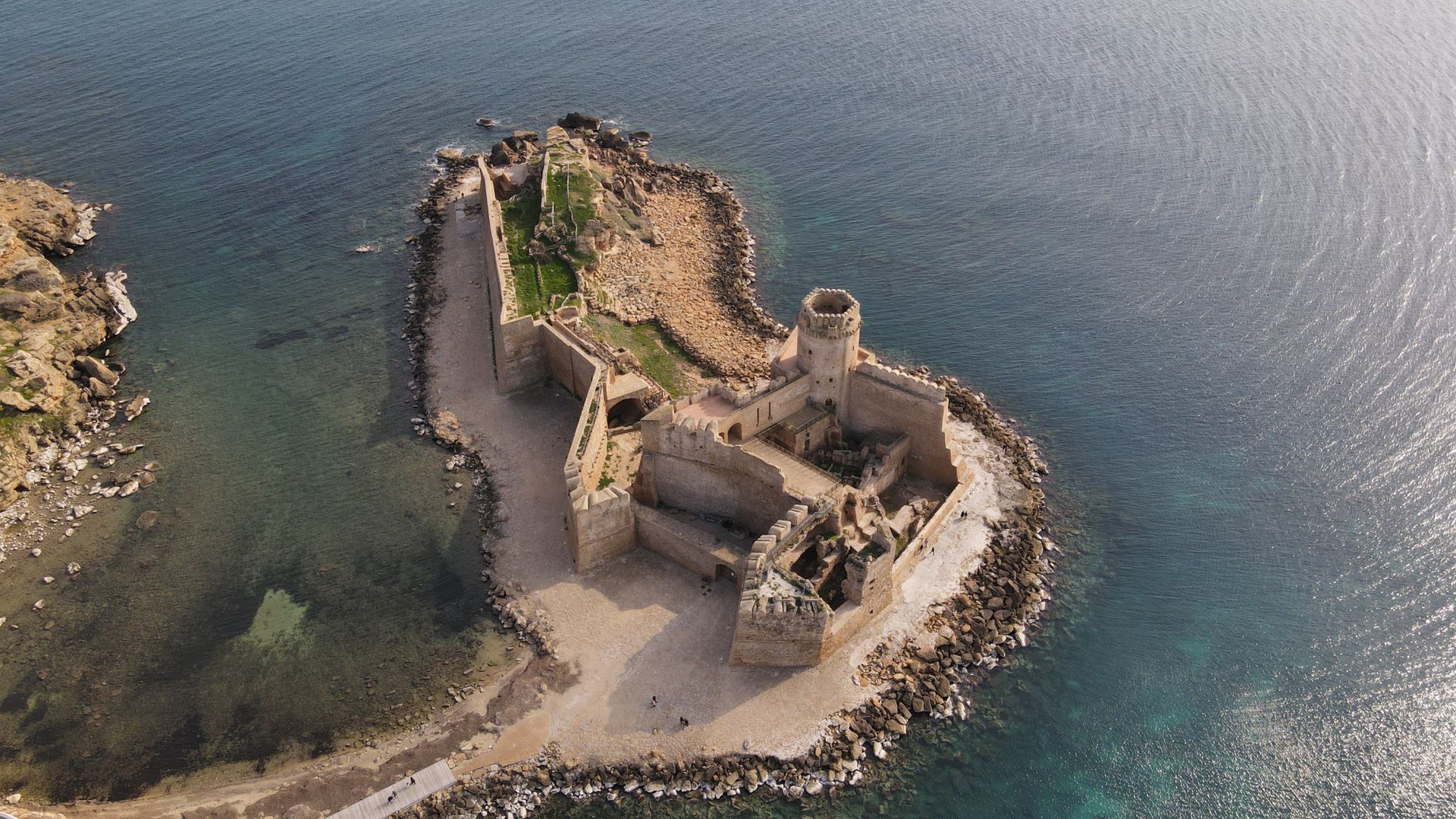 Stunning aerial shot of the historic Aragonese Castle on a rocky islet in Punta Delle Castella, Italy.
