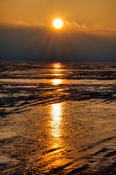 Sunrise reflecting on ocean waters, creating a serene and warm scene.