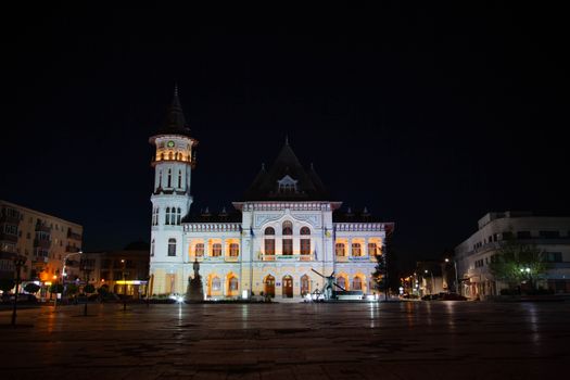 Night view of Buzau City Hall in Romania, beautifully lit against a dark sky, showcasing architectural elegance.
