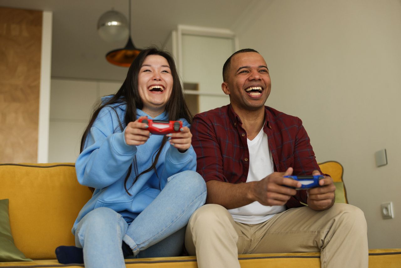 cheerful interracial couple having fun playing video games on a sofa s
