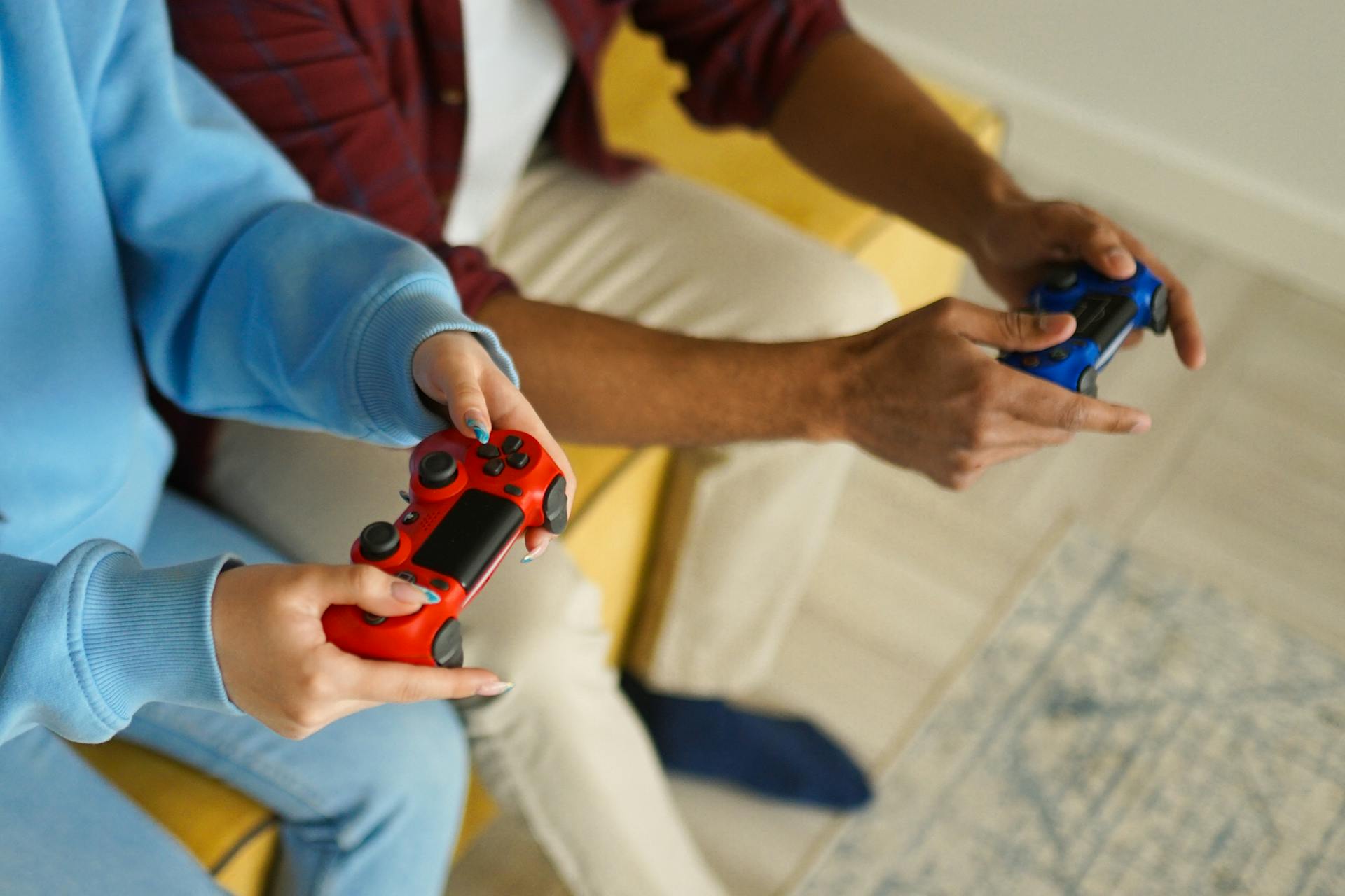 Two adults holding wireless game controllers while playing video games indoors.