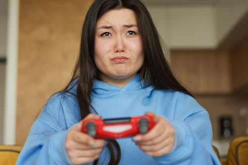 Close-Up Shot of a Woman in Blue Hoodie Playing Video Game