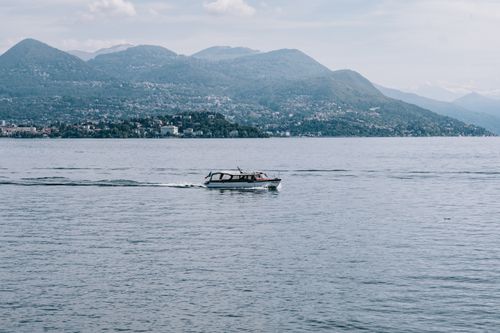 Free A boat glides across a calm lake with majestic mountain scenery in the background. Stock Photo