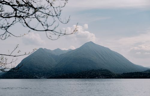Free Peaceful scene of mountains and lake under a clear blue sky with branches framing. Stock Photo