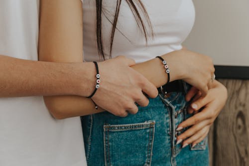 Crop romantic couple in bracelets embracing at home