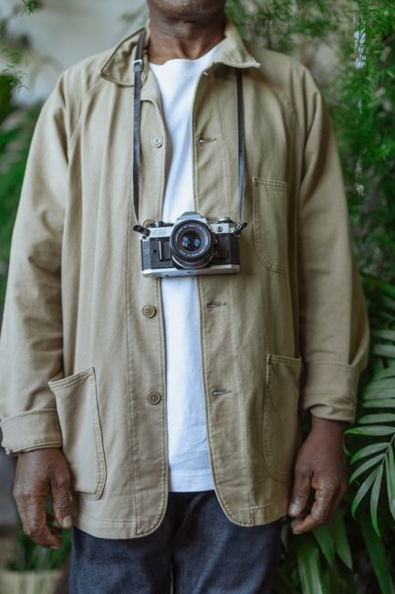 Close-up of a vintage camera hanging on an African American adult outdoors.