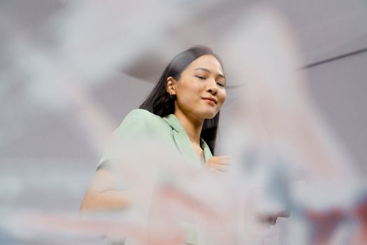 Portrait of a confident Asian woman smiling at work, captured indoors with a modern aesthetic.