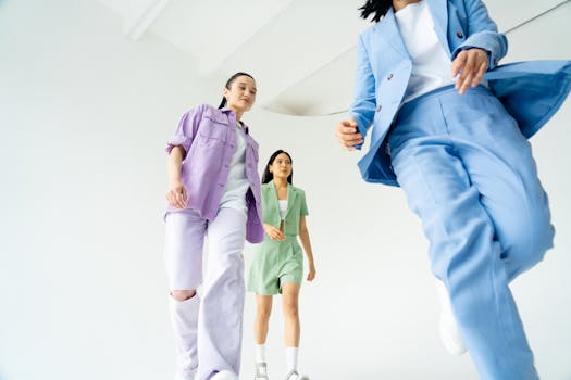 Dynamic low-angle shot of young women walking confidently in pastel suits, set against a bright studio background.