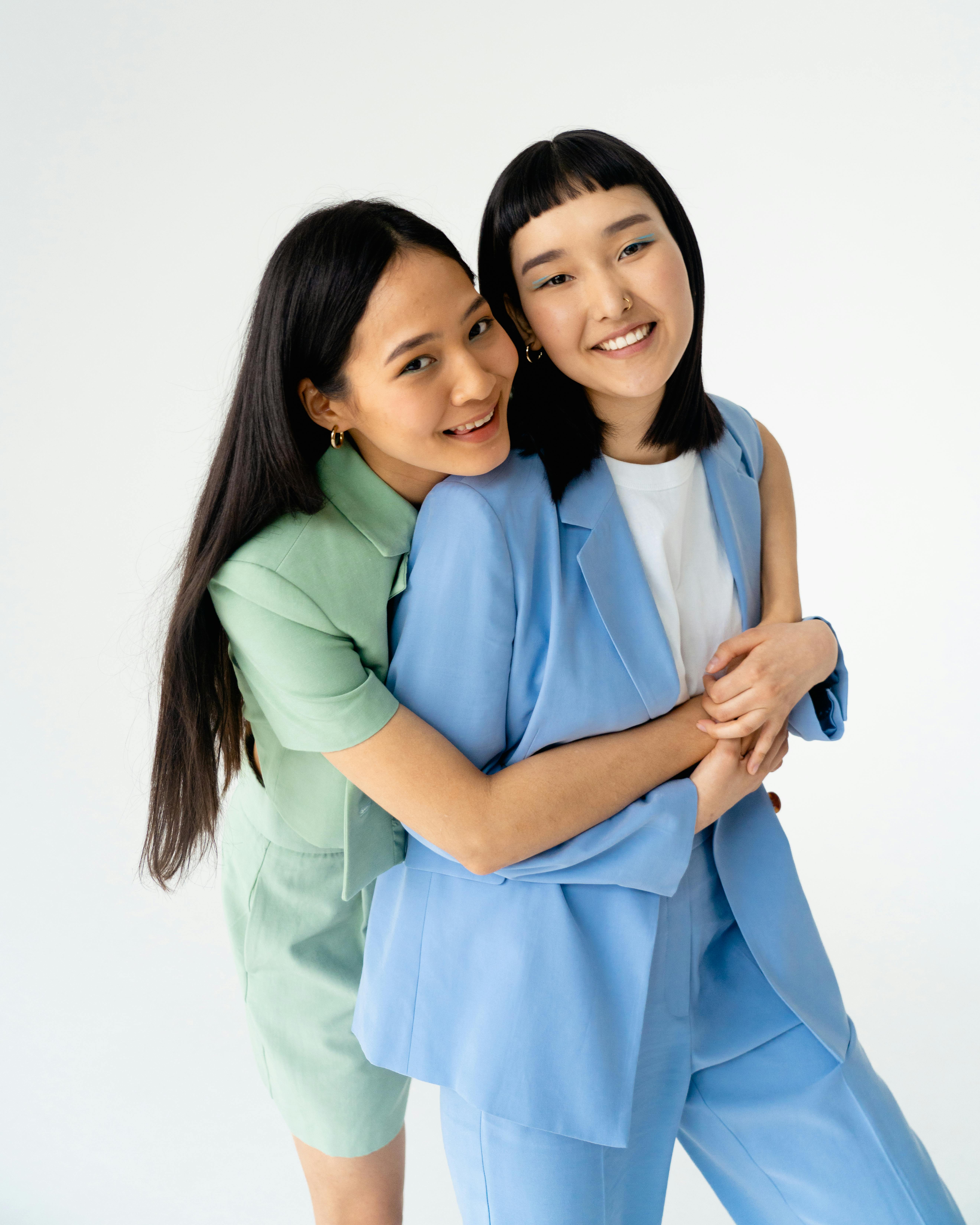 young women in trendy pastel outfits holding each other close