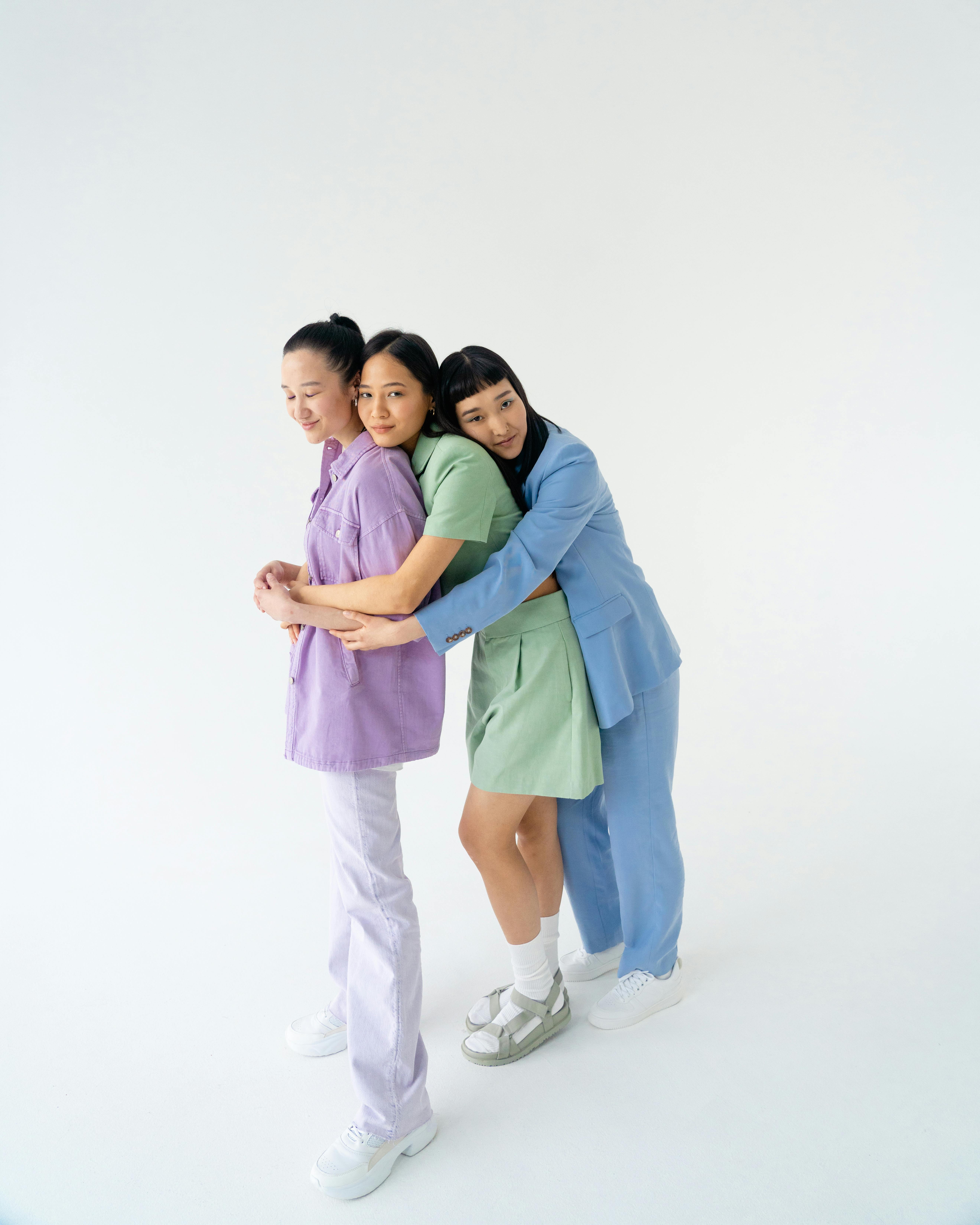 young women in trendy pastel outfits holding each other close