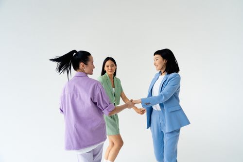 Free Three fashionable women holding hands, showcasing colorful pastel clothing in a studio setting. Stock Photo