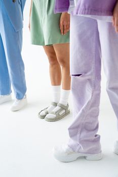 Stylish trio showcasing pastel fashion with white sneakers and sandals.