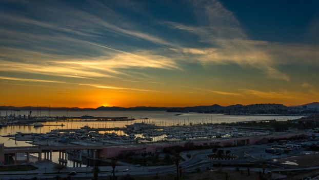 Beautiful sunset over a peaceful harbor with yachts and reflections in the water.