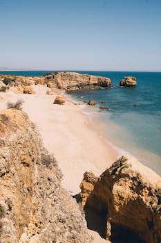 Explore the breathtaking rocky coastline of Praia da Marinha, Algarve, Portugal on a sunny day.