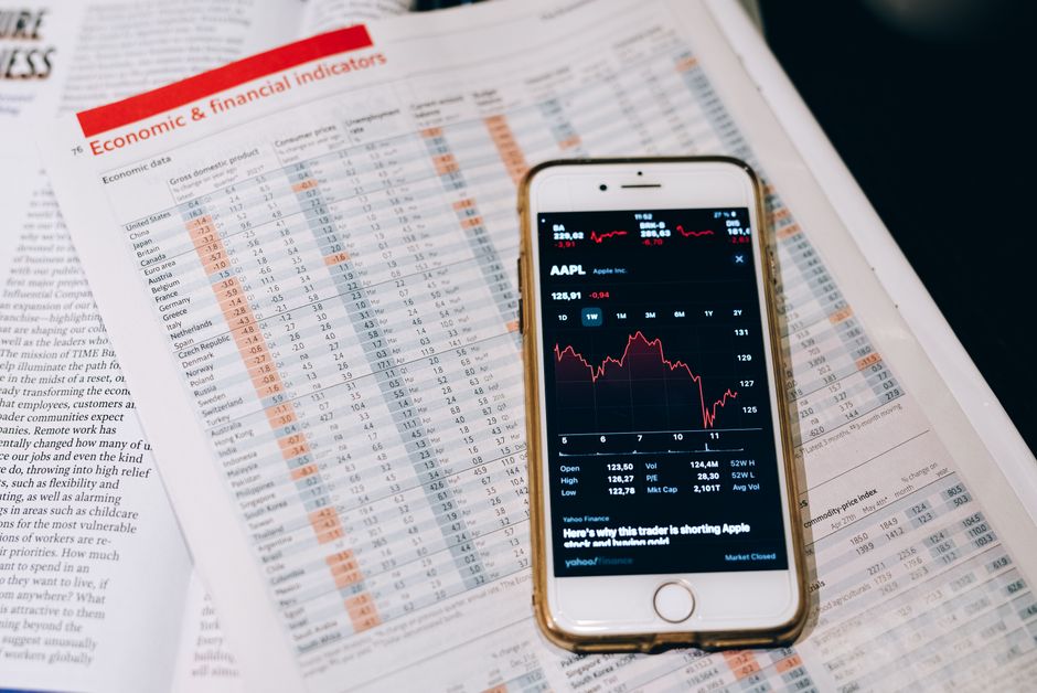 Смартфон с биржевыми данными на бумагах с финансовыми графиками