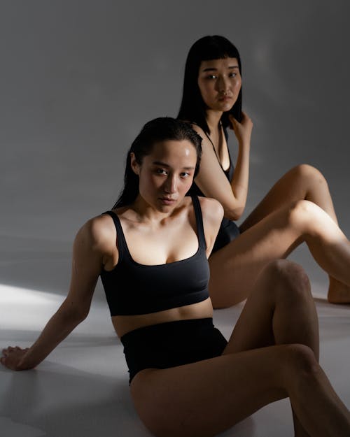 A Pair of Women in Black Bikini Sitting on the Floor