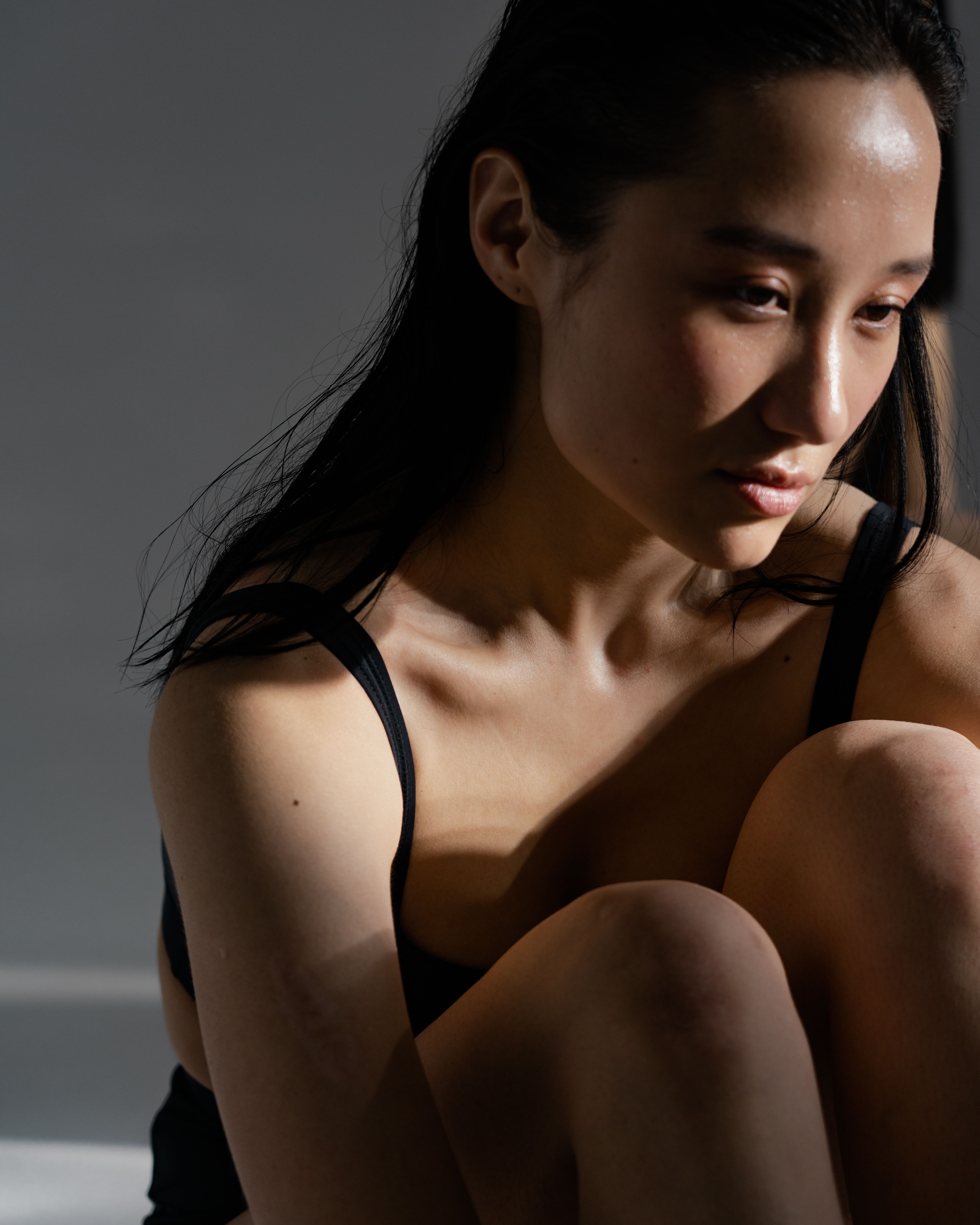 A thoughtful portrait of an Asian woman in soft studio lighting evoking introspection.