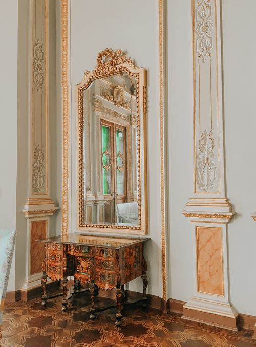 Free A beautifully ornate mirror reflecting elegant palace decor, highlighting historical interior design. Stock Photo
