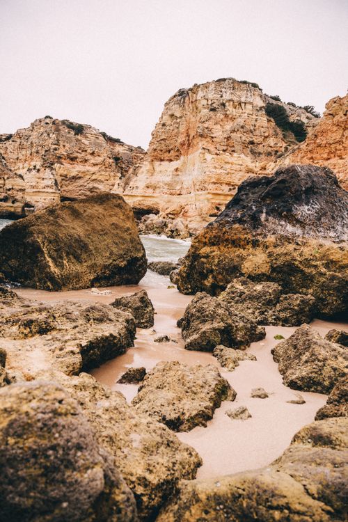 Free Explore the wild beauty of rocky cliffs meeting the sandy beach, showcasing nature's raw power. Stock Photo