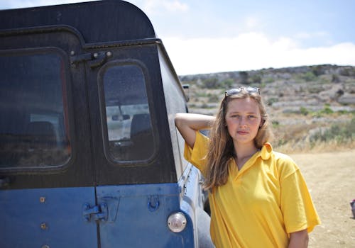 Femme Portant Un Polo Jaune Appuyé Sur Une Voiture