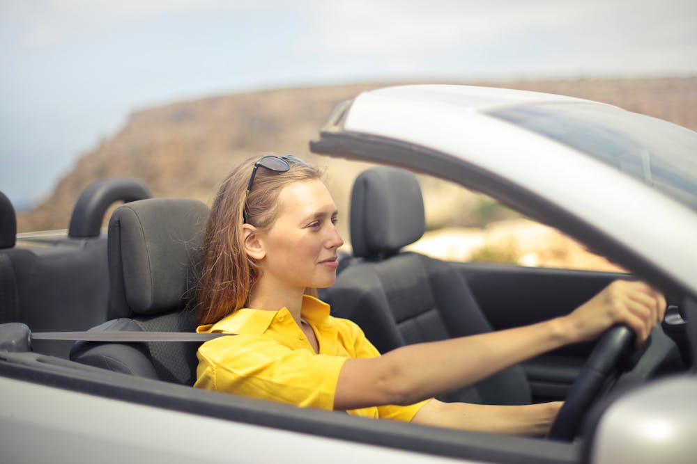 Woman in yellow shirt driving a silver car. | Photo: Pexels 