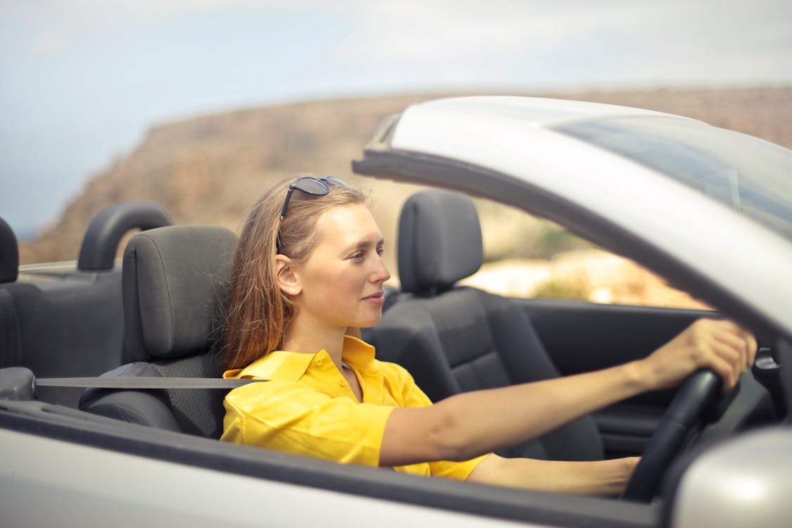Woman in Yellow Shirt Driving a Silver Car